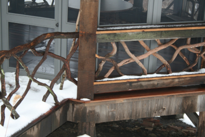 CLOSE-UP OF A RUSTIC RAILING ON A SCREENED FOLLY CRAFTED BY GEOFF FAIRBAIRN AT THE SAME HOME.